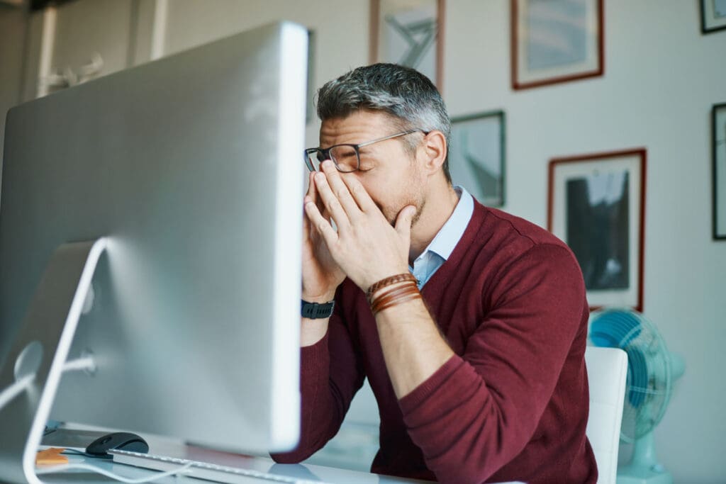 Man rests his eyes trying to prevent computer vision and digital eye strain.