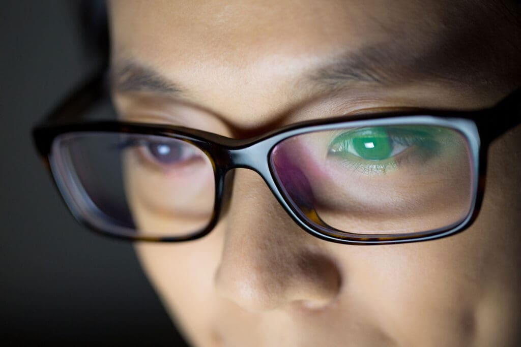 Woman works late at night on her computer using her prescription glasses.