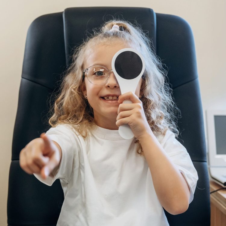Little girl is checking vision in the ophthalmologist cabinet.